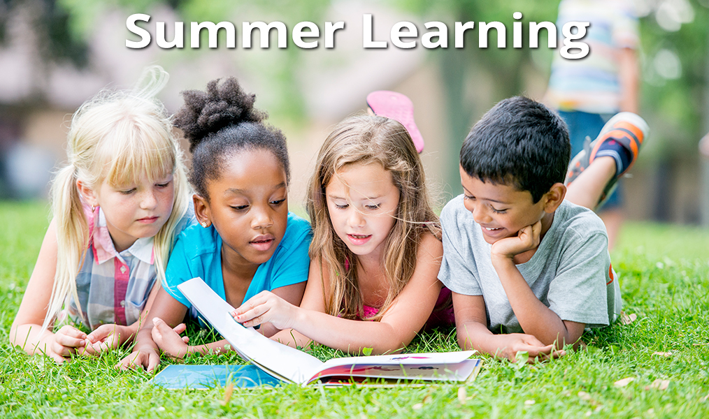Four students looking at a book with the words "Summer Learning."