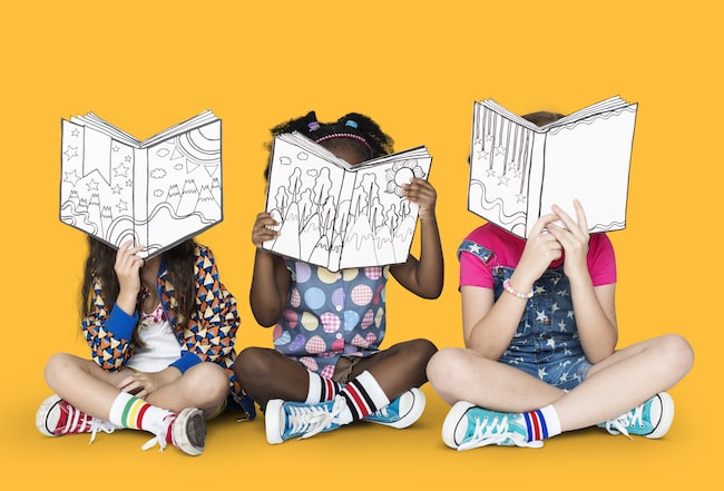 Three children reading books on a yellow backdrop